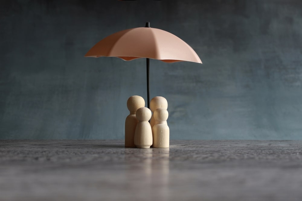 Wooden Human Figures Under An Umbrella